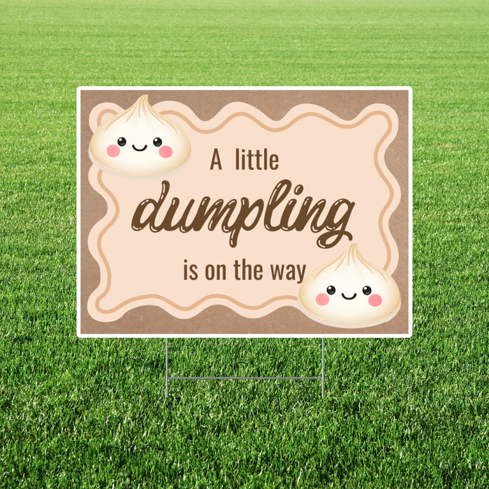 Rectangular yard sign with a warm beige background and wavy border, featuring cute smiling dumpling illustrations and the phrase “A little dumpling is on the way” in playful script, displayed on a lawn with a metal H-stake.