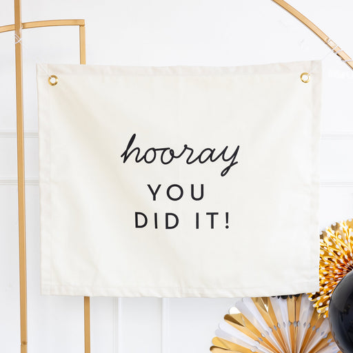 A 24-inch Graduation Hooray Canvas Banner  hanging on a wall.