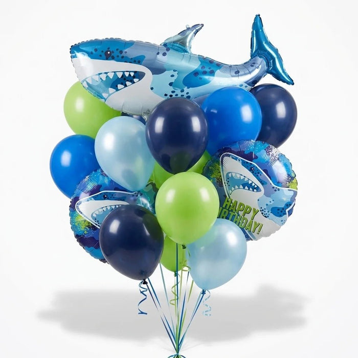 Shark birthday balloon bouquet featuring a large blue shark-shaped foil balloon, two round “Happy Birthday” shark foil balloons, and navy, blue, light blue, and lime green latex balloons with curling ribbons.
