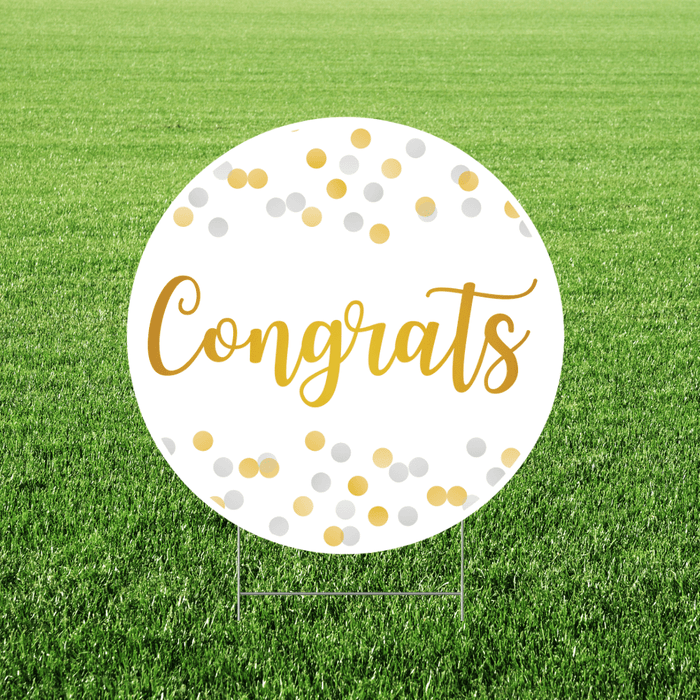 Congrats yard sign featuring a round white sign with gold script “Congrats” lettering and gold and silver confetti dots, displayed in grass.