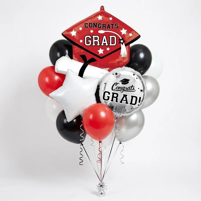 Graduation balloon bouquet featuring a red cap-and-diploma-shaped “Congrats Grad” foil balloon, a silver round “Congrats Grad!” foil balloon, a white star-shaped foil balloon, and red, black, white, and silver latex balloons with curling ribbons.