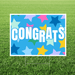 Congrats yard sign featuring a bright blue background with colorful star graphics, large white “Congrats” lettering with light blue shadowing, and a white rectangular border displayed in grass.