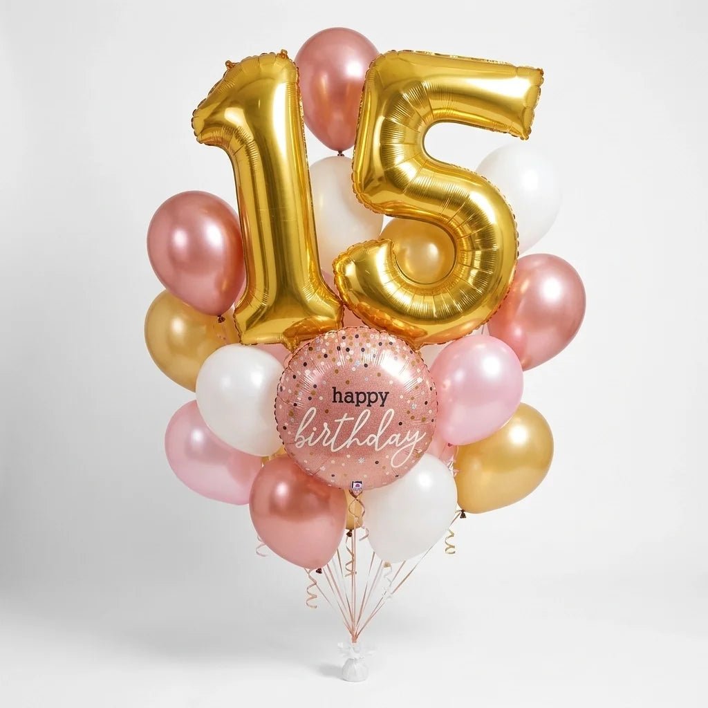 Customizable birthday balloon bouquet featuring large gold number balloons, a round rose gold “Happy Birthday” foil balloon, and rose gold, light pink, gold, and white latex balloons with curling ribbons.