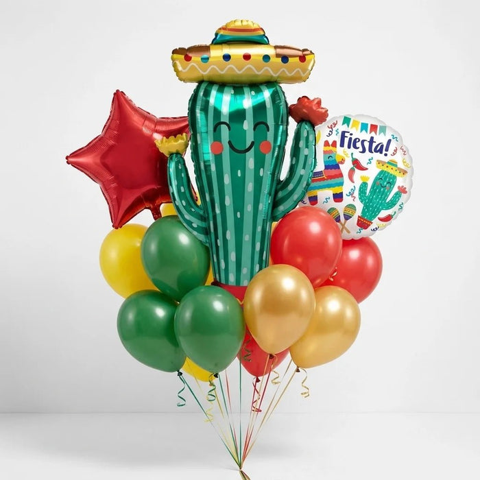 Fiesta cactus balloon bouquet featuring a smiling cactus-shaped foil balloon wearing a sombrero, a red star-shaped foil balloon, a round “Fiesta!” foil balloon, and red, yellow, green, and gold latex balloons with curling ribbons.