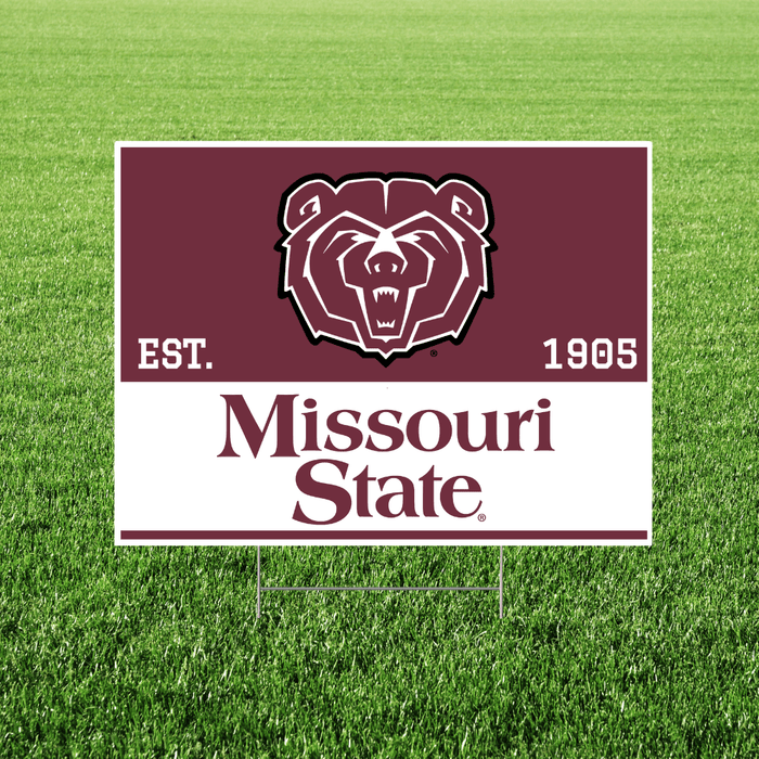 Missouri State logo on a maroon and white sign with a bear emblem on grass.