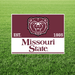 Missouri State logo on a maroon and white sign with a bear emblem on grass.