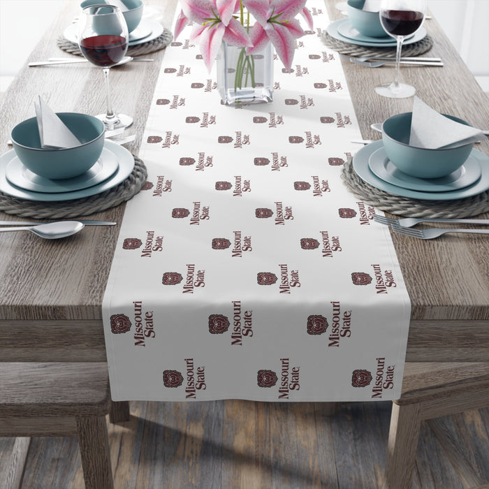 Table setting with a decorative table runner featuring Missouri state patterns on a wooden table.