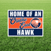 Sign with 'Home of an Olathe East Hawk' text and logo on a grass background