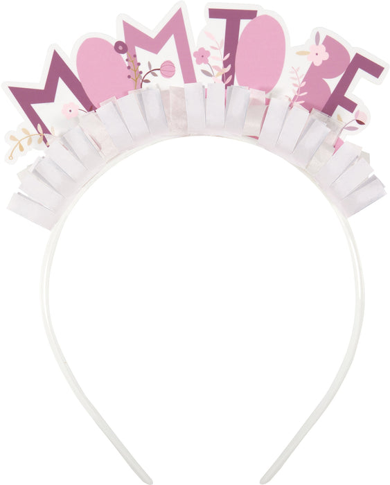 Mom-to-be headband featuring pink floral “Mom to be” lettering with white fringe accents on a white headband.