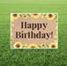 Happy Birthday sign with sunflower design on a grass background