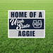 Sign with 'Home of a Utah State Aggie' text and logo on grass